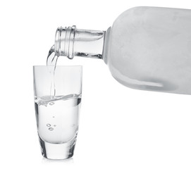 Pouring cold vodka into shot glass on white background