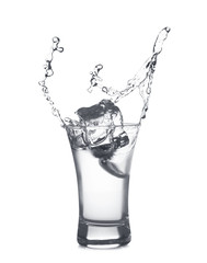 Ice cube falling into shot glass of vodka on white background