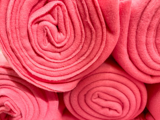 Fototapeta premium Many rolled up pink colorful fleece blankets close up in a store, home comfort concept