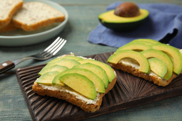 Tasty avocado toasts served on blue wooden table, closeup