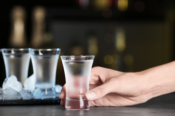 Woman with shot of vodka at table in bar, closeup - obrazy, fototapety, plakaty