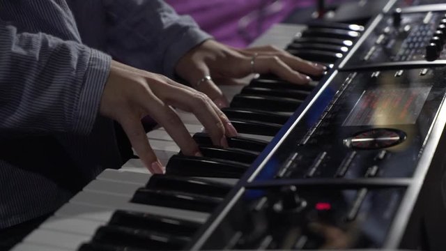  female hands play on a synthesizer closeup