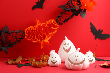 Obraz premium Composition with pumpkin shaped candle holders on red background. Halloween decoration