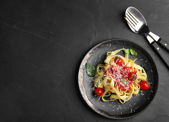 Tasty pasta and cutlery on black table, flat lay. Space for text