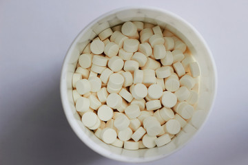 white round tablets in white jar in medical healthcare drugstore concept,closed up
