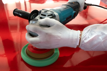 Tools and means for polishing. Glossy red surface. Professional car service - worker polishes a detail of a red car. Hand polishing tool. Motion blur.