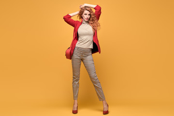 Fashionable woman in Trendy autumn spring outfit, stylish wavy hair, makeup. Joyful lady in red...