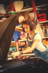 Obraz na płótnie Canvas woman mechanic with a wrench adjusts the car's engine