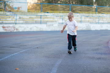 Little boy running on a treadmill at the stadium. Education, healthy lifestyle.