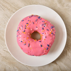 Donut with pink frosting and candy sprinkles