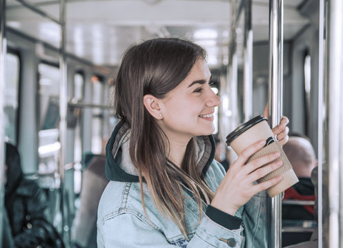 Young woman drinking coffee on public transport.
