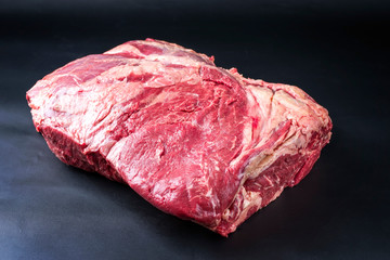 Raw dry aged wagyu beef shoulder clod roast as closeup on black background with copy space