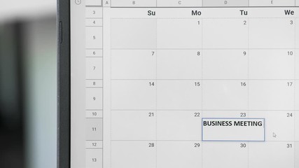 Writing BUSSINES MEETING on 23th on calendar to remember this date.