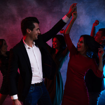 Tango dancers. A young smartly dressed couple is holding hands, while dancing with their three friends, celebrating New Year or Christmas Eve.