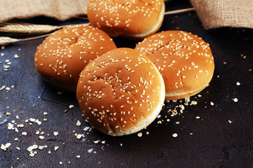 Fresh homemade burger buns with sesame on dark background