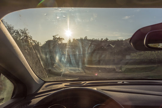 Dreckige Windschutzscheibe eines Autos mit Schlieren als Sichtbehinderung im Sonnenschein