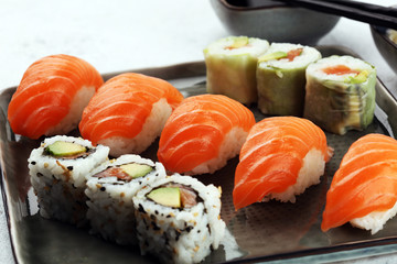 close up of sashimi sushi set with chopsticks and soy - sushi roll with salmon and sushi roll with...
