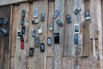 old mobile phones nailed to a wooden wall