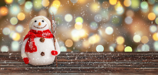 Snowman covered with snowflakes on wooden surface. Christmas background. Copy space.