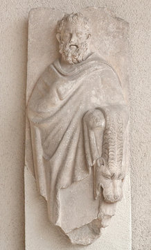 Ancient stone bas-relief with Heracles and skin of Nemean lion on ancient Greek funerary stele