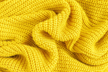 Crumpled soft knitted fabric of yellow fluffy woolen yarn closeup, beautiful cozy background