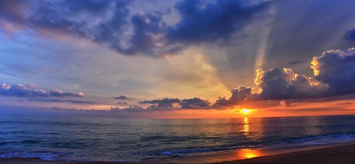 Phuket beach sunset, colorful cloudy twilight sky reflecting on the sand gazing at the Indian Ocean, Thailand, Asia.