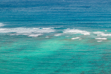 Obraz premium Beautiful blue green turquoise teal shallow tropical water with waves breaking on a coral reef on Oahu, Hawaii, USA