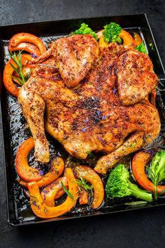 Barbecue spatchcocked chicken al mattone chili with pumpkin and broccoli as closeup on an old metal tray