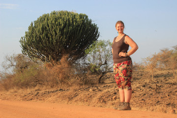 White young full fat European woman tourist standing in the African savannah in Uganda against the...