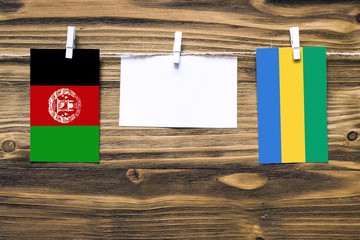Hanging flags of Afghanistan and Gabon attached to rope with clothes pins with copy space on white...