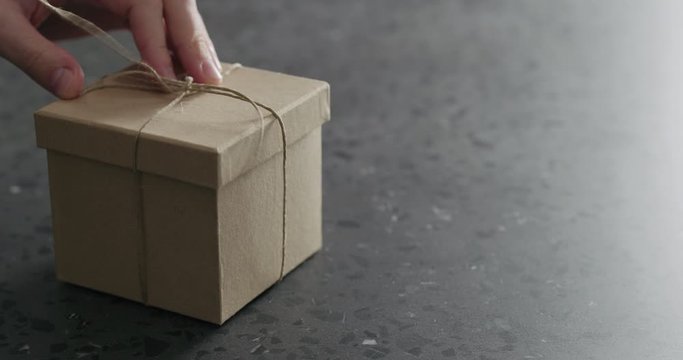 Slow motion man hand open brown paper gift box on terrazzo countertop
