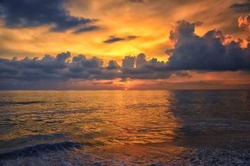 Phuket beach sunset, colorful cloudy twilight sky reflecting on the sand gazing at the Indian Ocean, Thailand, Asia.
