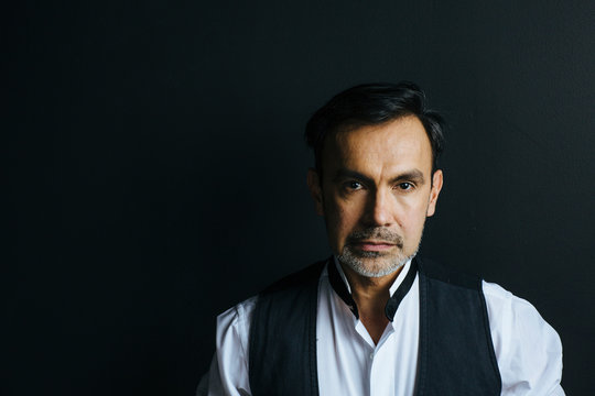 Portrait of a  serious man in vest isolated on black studio background
