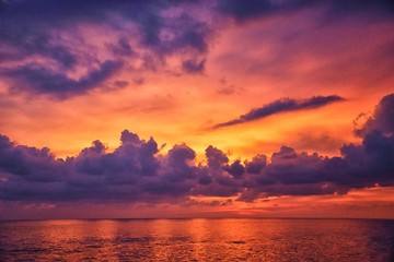 Phuket beach sunset, colorful cloudy twilight sky reflecting on the sand gazing at the Indian Ocean, Thailand, Asia.