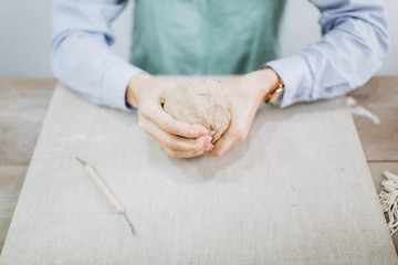 The potter's hands are shaped a cup from a clay. The process of creating pottery. The master ceramist works in his studio. Close-up, only hands. Crockery from clay own hands.