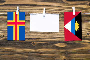 Hanging flags of Aland Islands and Antigua and Barbuda attached to rope with clothes pins with copy...