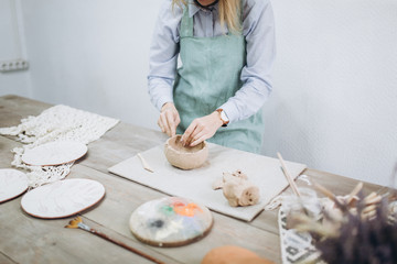 The potter's hands are shaped a cup from a clay. The process of creating pottery. The master ceramist works in his studio. Close-up, only hands. Crockery from clay own hands.