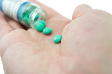 multicolored tablets of different size in hand top view close-up macro, isolated, white background