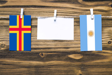 Hanging flags of Aland Islands and Argentina attached to rope with clothes pins with copy space on...