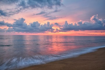 Phuket beach sunset, colorful cloudy twilight sky reflecting on the sand gazing at the Indian...