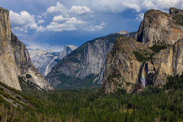 Half dome in the distance and a brilliant rainbow waterfall on the right from Artist Point Trail in Yosemite national park