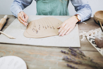 The potter's hands are shaped a cup from a clay. The process of creating pottery. The master ceramist works in his studio. Close-up, only hands. Crockery from clay own hands.