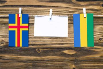 Hanging flags of Aland Islands and Gabon attached to rope with clothes pins with copy space on...