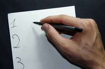 The male left and right hand holds a pen over a white sheet of paper on a black background. Items per sheet, Sports and Fitnec