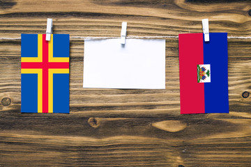 Hanging flags of Aland Islands and Haiti attached to rope with clothes pins with copy space on...