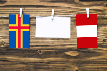 Hanging flags of Aland Islands and Peru attached to rope with clothes pins with copy space on white...