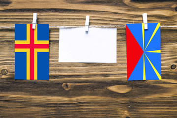 Hanging flags of Aland Islands and Reunion attached to rope with clothes pins with copy space on...