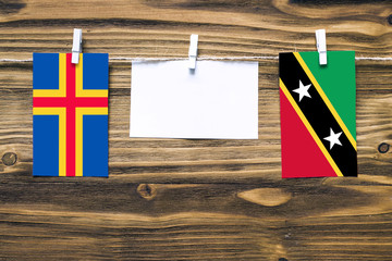 Hanging flags of Aland Islands and Saint Kitts And Nevis attached to rope with clothes pins with...