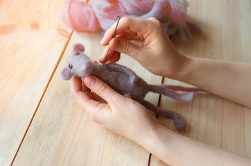 felting wool toy close-up hands on wooden background