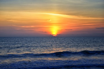 Phuket beach sunset, colorful cloudy twilight sky reflecting on the sand gazing at the Indian Ocean, Thailand, Asia.